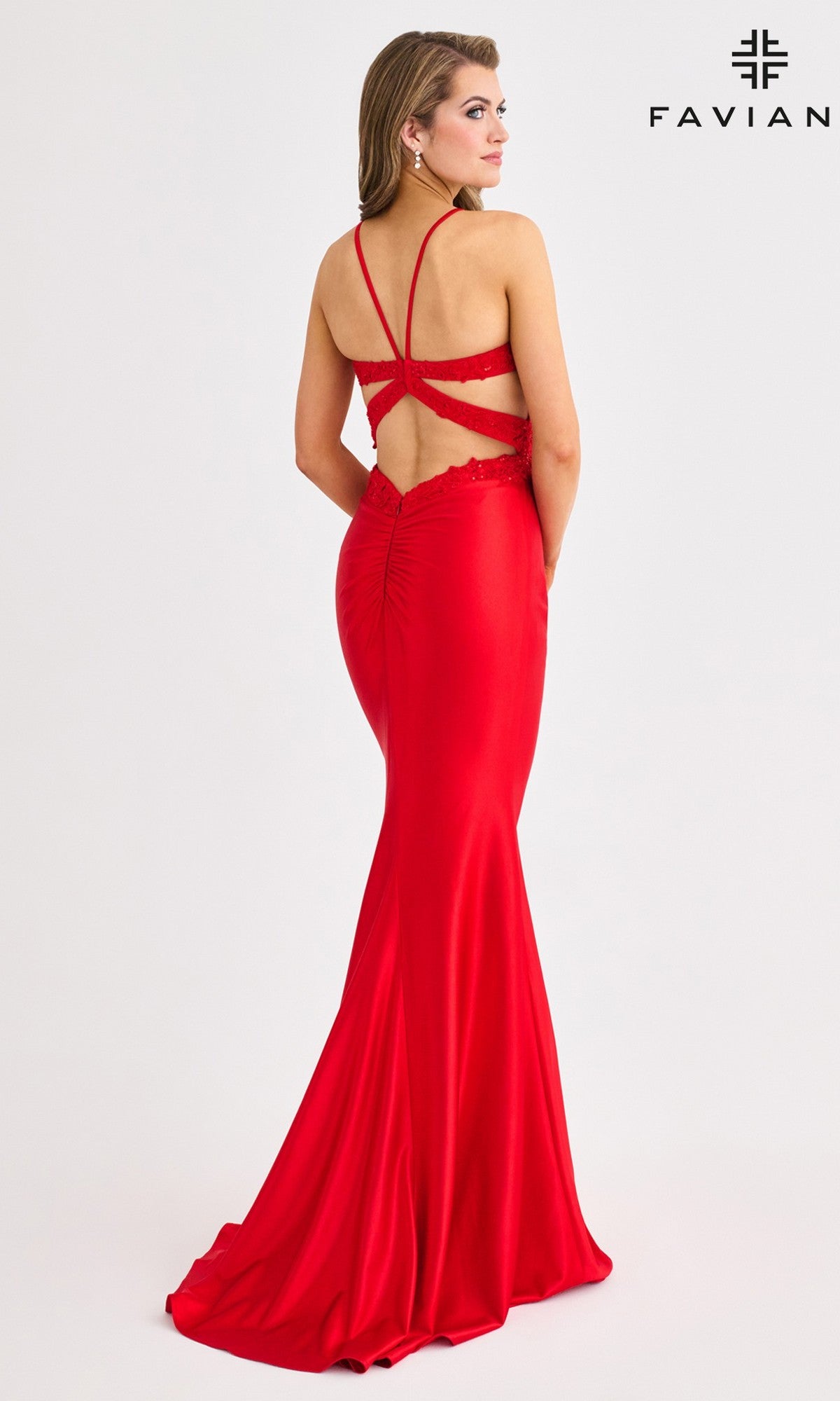 A woman models the Faviana 11414, a long, fitted red satin prom dress with lace embroidery and an open strappy back, posing in front of a plain white background.